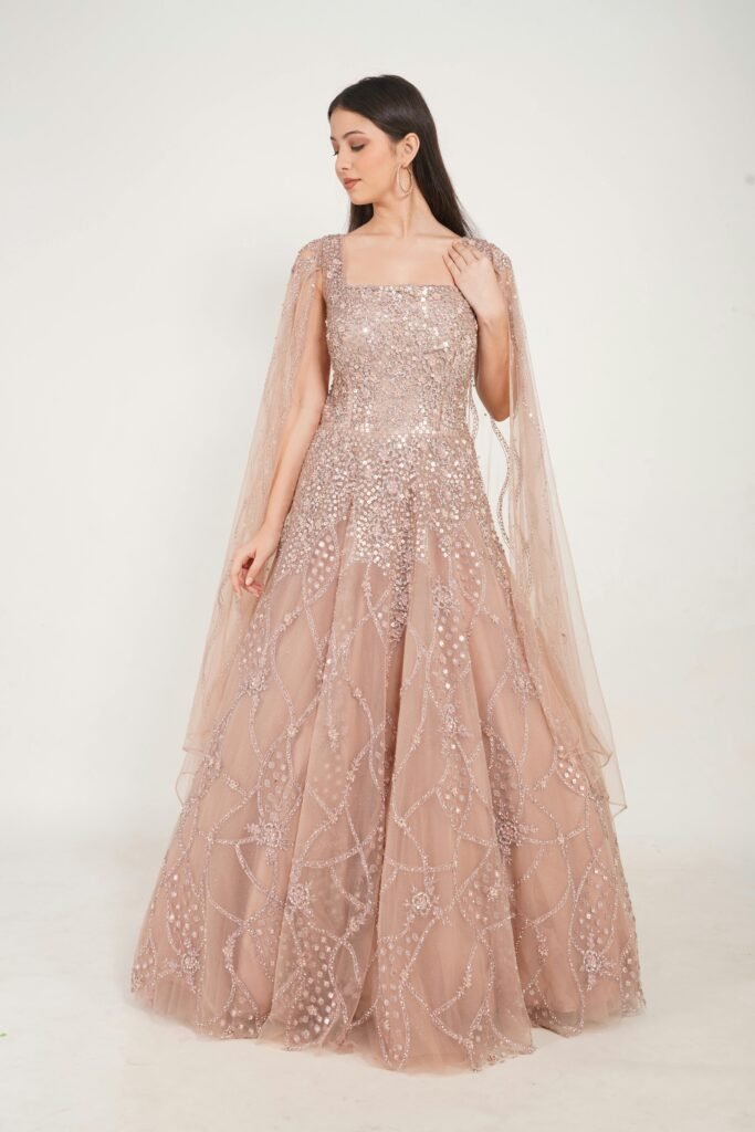 A stylish woman in a glittering gown poses in a studio setting.